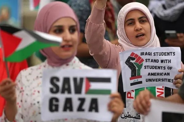 دانشجویان دانشگاه عراق، پرچم و پلاکاردهای فلسطین را در حین تظاهرات در محوطه دانشگاه بغداد حمل می کنند.