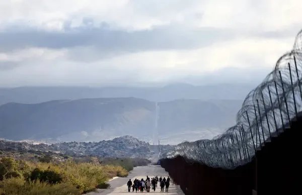 کالیفرنیا، ایالات متحده ـ مهاجران پناهجو پس از عبور از یک شکاف در مانع به سمت یک کمپ موقت می روند تا منتظر رسیدگی توسط گشت مرزی ایالات متحده باشند.