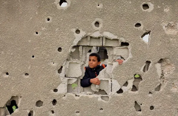 یک کودک فلسطینی در شهر غزه از سوراخ دیواری خانه اش که بر اثر تهاجم اخیر صهیونیست ها تخریب شده، به بیرون نگاه می کند. /ZUMA

