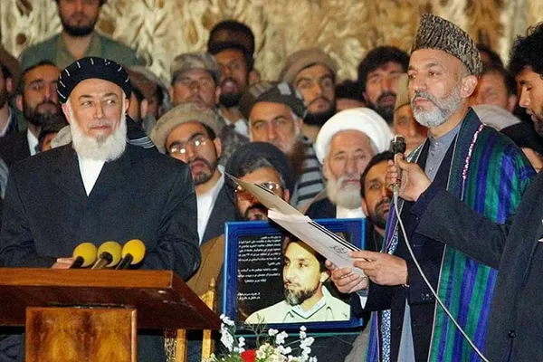 2001: حامد کرزای و برهان الدین ربانی در خلال مراسم تحلیف دولت جدید افغانستان در کنار تصویر احمد شاه مسعود