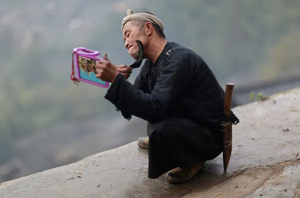 یک مرد چینی در روستایی در استان گوئیژوئوی این کشور مشغول اصلاح صورت خود با یک داس است. (Reuters)
