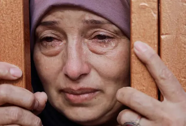 خان یونس، نوار غزه ــ گریه یک زن در حالی که از پشت دروازه به سوگ فلسطینیان شهید شده در حملات اسرائیل نگاه می کند.