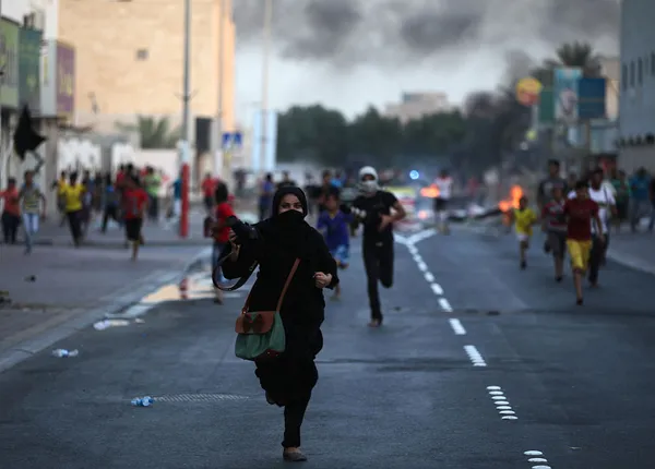 عکاسان در حال فرار از محل انتشار گاز اشک آور پلیس بحرین که برای متفرق کردن تظاهرکنندگان بر علیه سیاستهای دولت تجمع کرده بودند/AP
