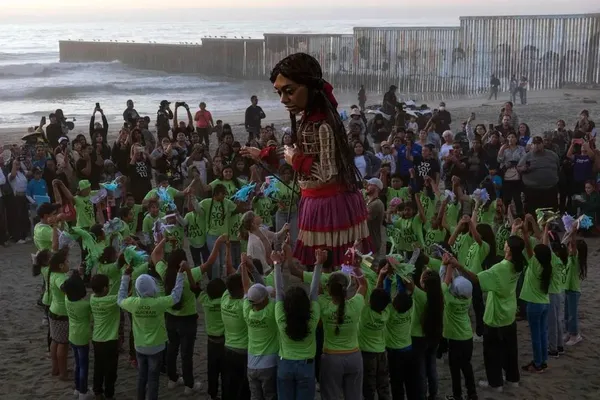 Playas de Tijuana، مکزیک
امل کوچولو، عروسک 12 فوتی که نماینده یک کودک 10 ساله پناهنده سوری است، با کودکان مهاجر در نزدیکی دیوار مرزی آمریکا و مکزیک در باخا کالیفرنیا
