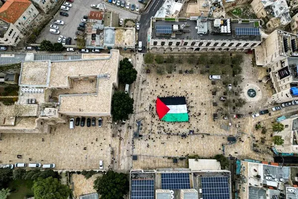 بیت لحم، کرانه باختری ــ به اهتزاز درآمدن پرچم عظیم فلسطین همزمان با تجمع مردم در شب کریسمس در میدان منگر، خارج از کلیسای ولادت 
