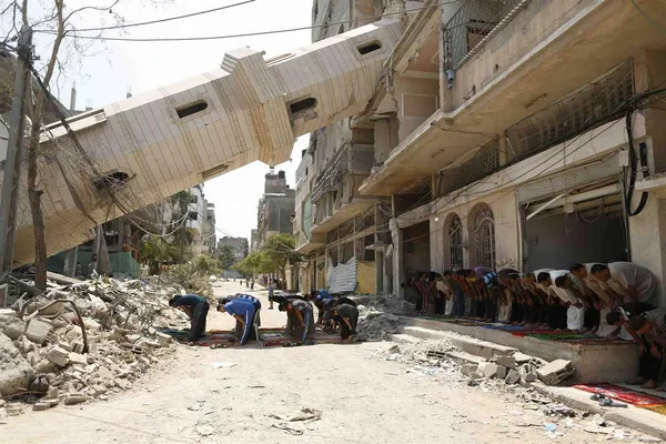 نماز جماعت فلسطینی&zwnj;ها در زیر مناره سقوط کرده در غزه. تا کنون نزدیک ۲۰۰۰ فلسطینی که نزدیک به ۹۰ درصدشان غیر نظامی هستند در جنگ نا&zwnj;برابر با صهیونیست&zwnj;ها به شهادت رسیدند و از سویی دیگر رژیم اسرائیل اعلام کرده تعداد۶۴ نفر از صهیونیست&zwnj;ها در این جنگ کشته شده&zwnj;اند. /Reuters
